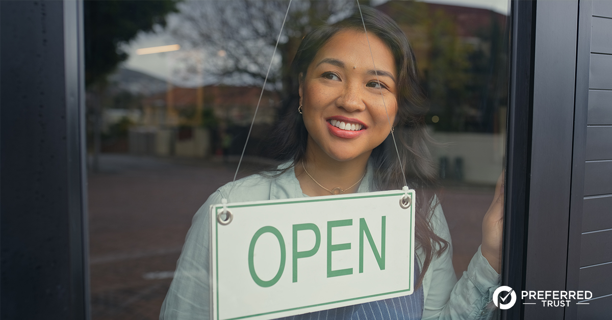 Business owner looking out window with an open sign in the window